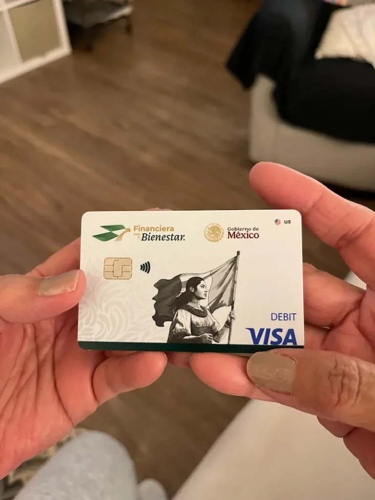 Manos de una mujer sosteniendo uan tarjeta de débito Finabien en una sala, destacando el control de las finazas y el ahorro seguro.