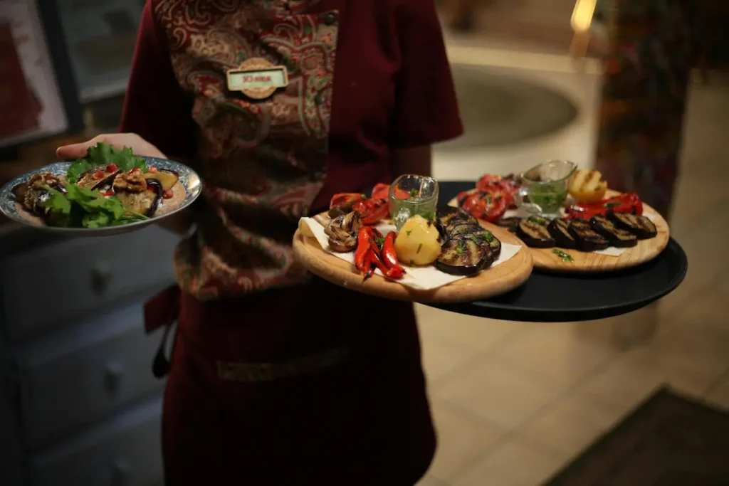 Una mesera sosteniendo tres platos de comida, ilustrando el esfuerzo físico y la adaptación laboral después de los 50 años.